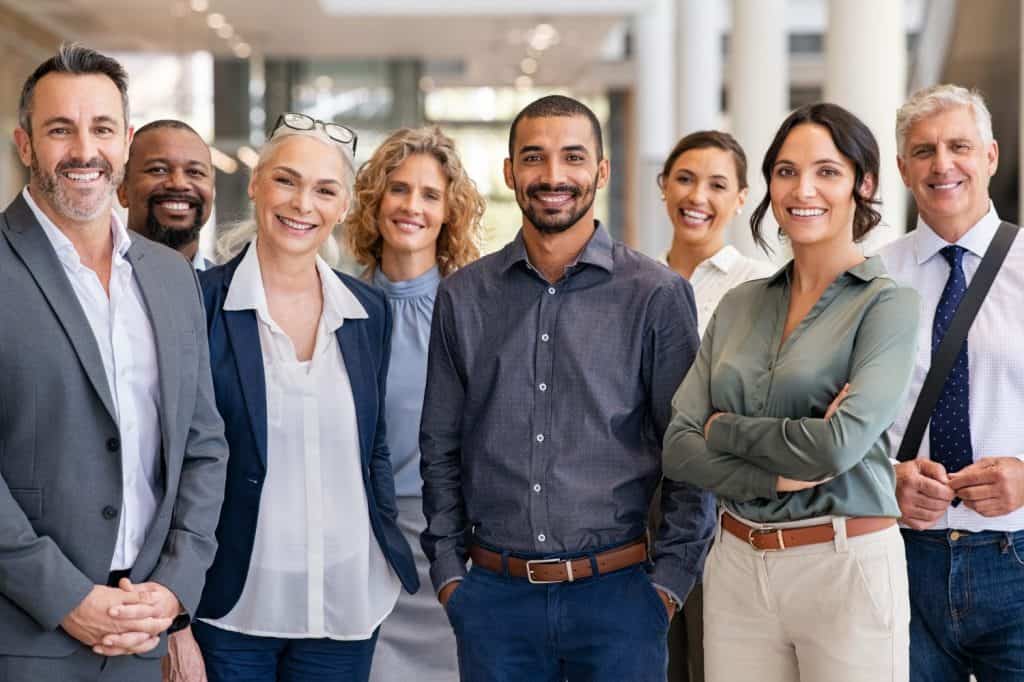 Portrait of successful group of business people at modern office looking at camera. Portrait of happy businessmen and satisfied businesswomen standing as a team. Multiethnic group of people smiling.