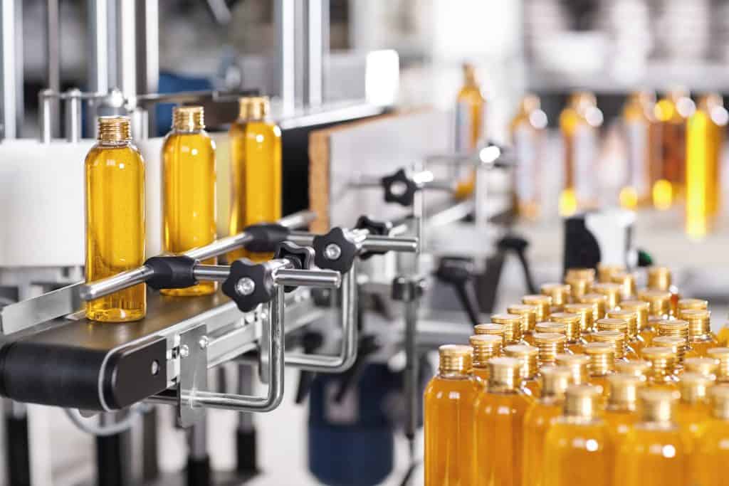 Production line of beauty and healthcare products at plant or factory. Process of manufacturing and packaging cosmetics goods. Glass or plastic bottles with screw caps standing on conveyor belt