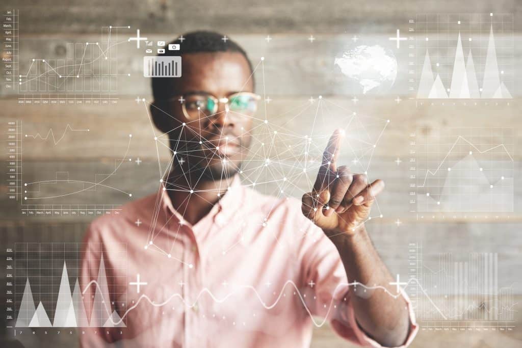 Visual effects. Future technology touch screen interface. Handsome African American businessman in shirt touching screen interface, drawing a chart in futuristic office. Selective focus on the hand