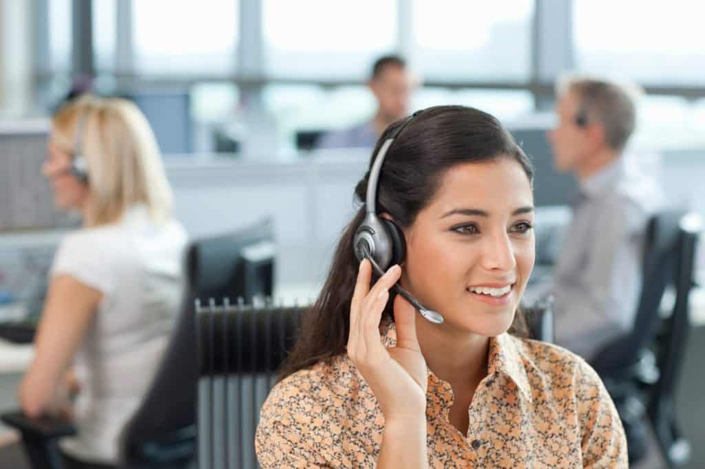 A horizontal view of a confident businesswoman in selective focus talking into the headset while sitting at her desk