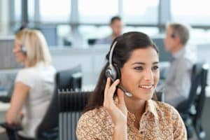 A horizontal view of a confident businesswoman in selective focus talking into the headset while sitting at her desk