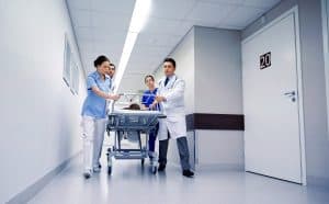profession, people, health care, reanimation and medicine concept - group of medics or doctors carrying unconscious woman patient on hospital gurney to emergency