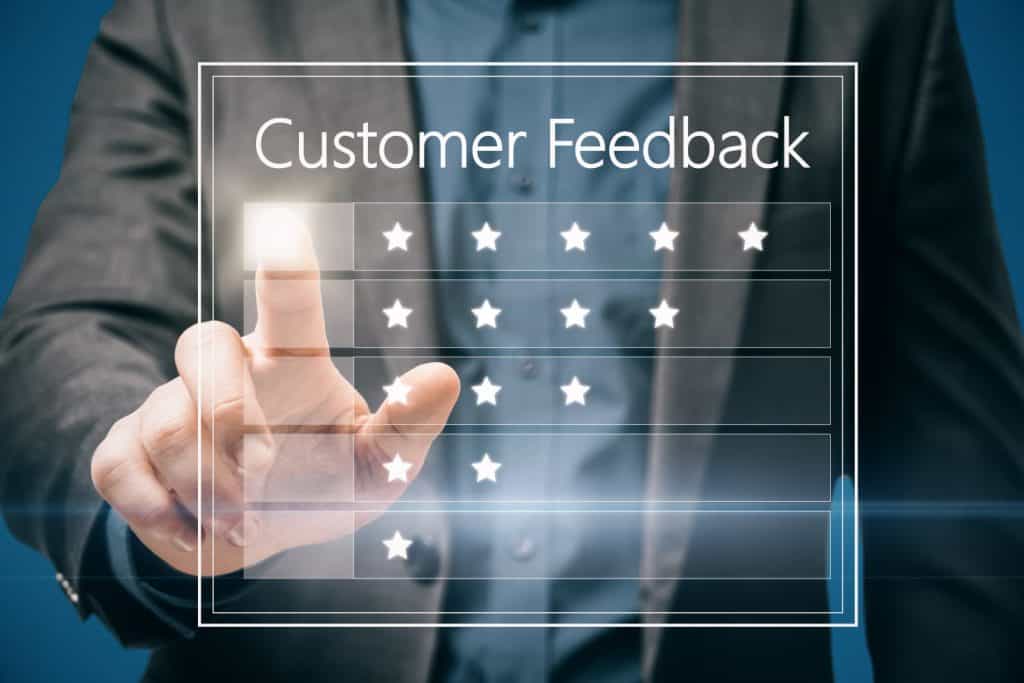 Close up of business man hand pointing at customer feedback hologram on blue background. Rating and ranking concept