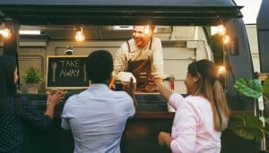 Multiracial people ordering food at counter in food truck outdoor - Soft focus on chef man face